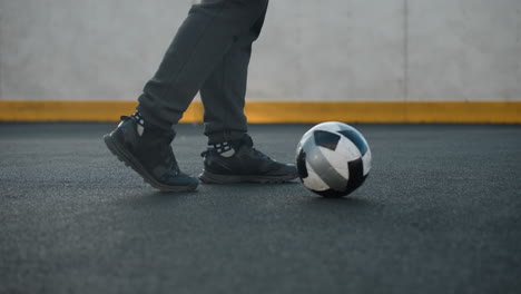 side leg view of athlete showcasing precise ankle twists with left and right leg, skillfully maneuvering soccer ball in sport arena featuring painted wall