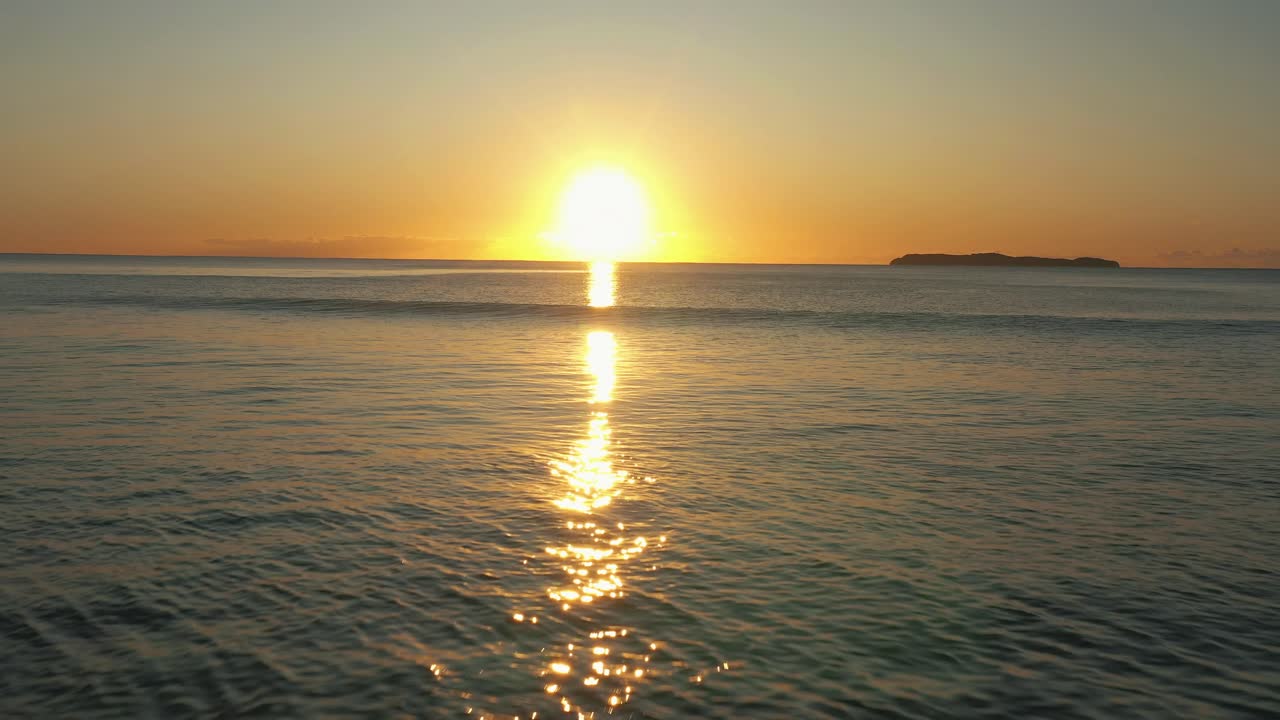 Flying near the water from the beach to the ocean sunrise