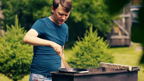 Nahaufnahme-Eines-Mannes-In-Zeitlupe,-Der-Pilaw-In-Einem-Kessel-Auf-Kohlen-Auf-Einem-Grill-Kocht-Und-Das-Fleisch-Umrührt