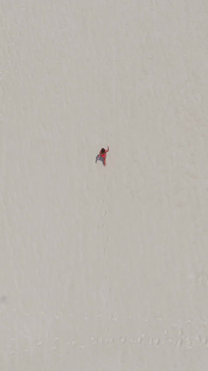 Vertical Top Down Aerial View Tracking Woman Walking on White Sand Beach