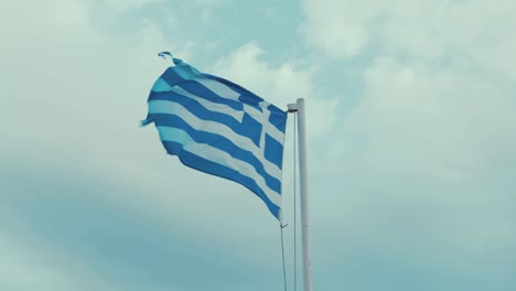 worn greek flag blowing in the wind overcast sky 60fps