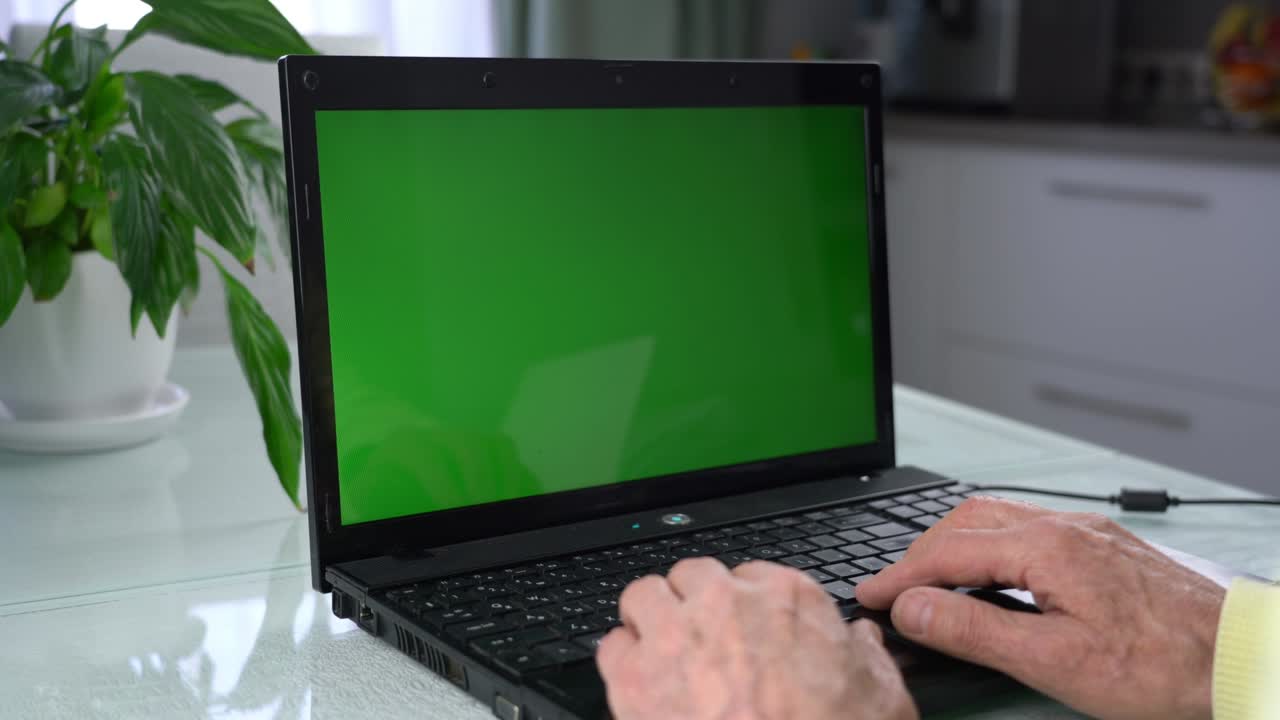 hombre mayor con manos arrugadas escribiendo en el teclado de una computadora portátil