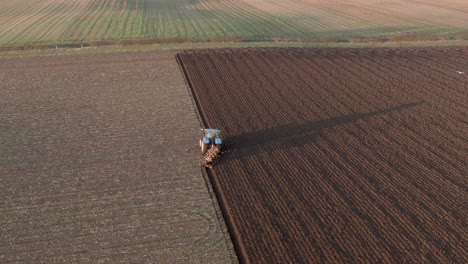 Aerial-view-of-a-farm-tractor-ploughing-a-field-in-Aberdeenshire-on-a-sunny-day,-Scotland