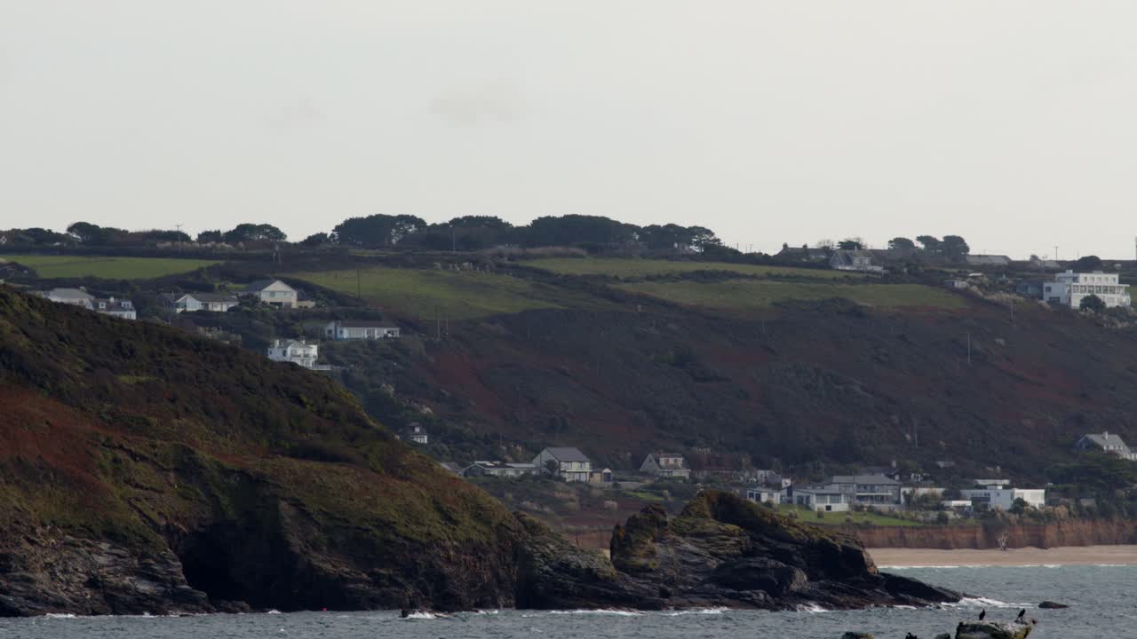 fotografía a distancia del promontorio con la playa de praa sands en el fondo