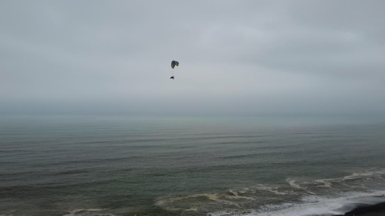 video de drones de un parapente motorizado o triciclo volando sobre las olas del océano en lima, perú