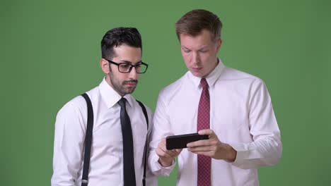dos jóvenes empresarios multiétnicos trabajando juntos contra un fondo verde