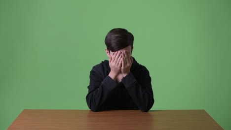 young handsome iranian teenage boy against green background