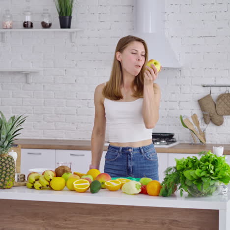 young woman eating fresh apple. pretty girl coming to the table with organic fruit and vegetables and taking juicy apple. healthy food concept.