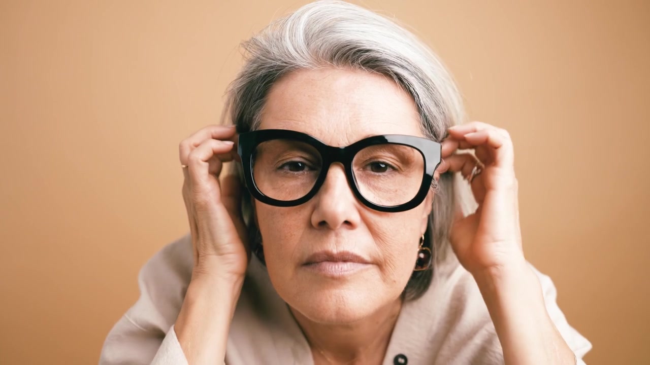 Donna matura con capelli grigi che applica il balsamo labbra