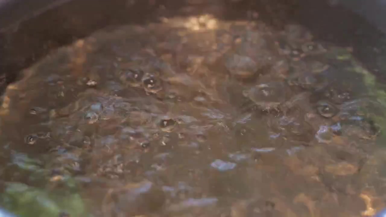 Close-up of a steaming shabu shabu hot pot with vigorously bubbling broth, rising steam, and a rich savory soup base ready for cooking.