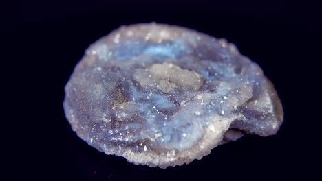 girando sin problemas un mineral azul (rosa calcedónica) frente a un fondo negro