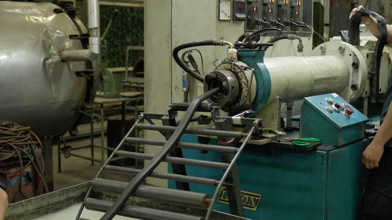 Factory workers working on a rubber extrusion at a manufacturing plant in the outskirts of Bangkok, Thailand.