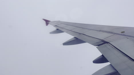 the wing of a flying passenger plane amidst dense clouds in the sky