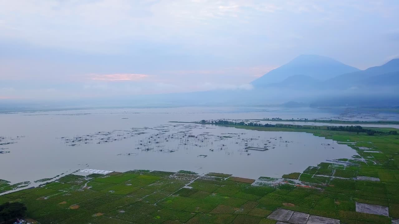 배경에 일출 하늘과 산이 있는 거대한 호수의 드론 샷