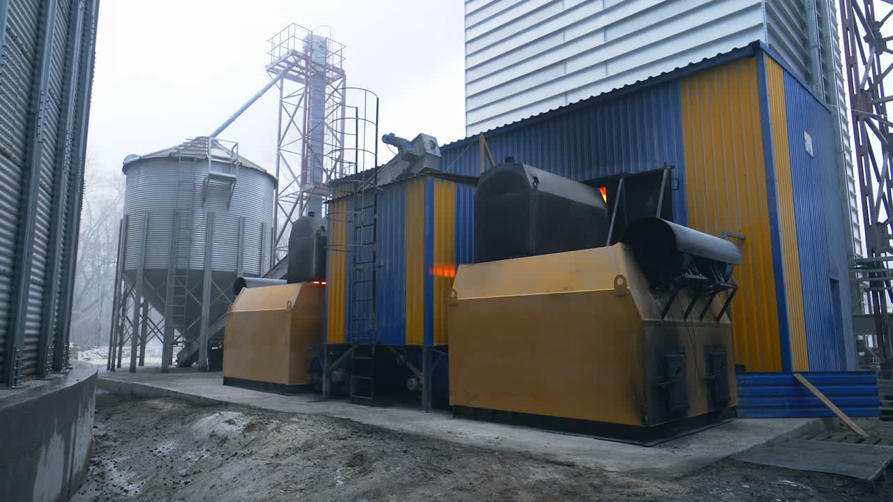 Industrial premises at the territory of modern granary plant. Furnace room for heating the elevators from outside. Winter sky background.