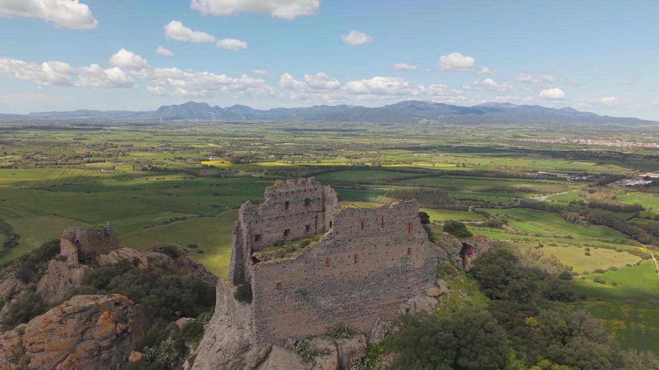 Castello di Acquafredda no topo de uma colina perto de Siliqua, no sul da Sardenha, Itália, rodeado por terreno acidentado e paisagem rural. Imagem aérea ampla.