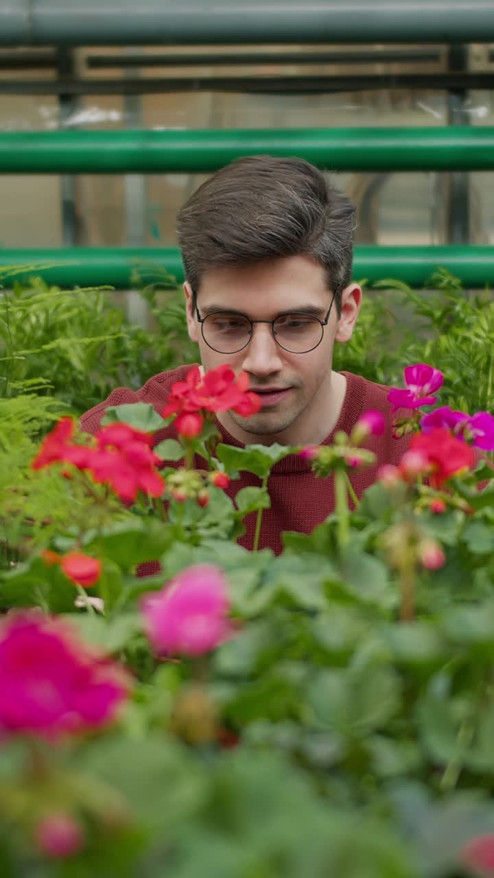 Man smelling flowers in a greenhouse