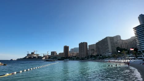 Monaco-Larvotto-Beach-at-sunset-with-adjacent-multi-story-buildings,-Monaco