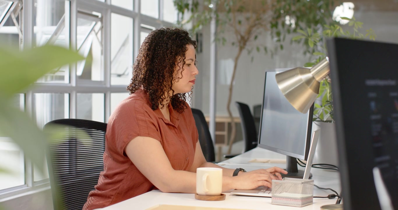 Donna afroamericana concentrata sul monitor alla scrivania mentre digita sulla tastiera, finendo il lavoro, spazio copia