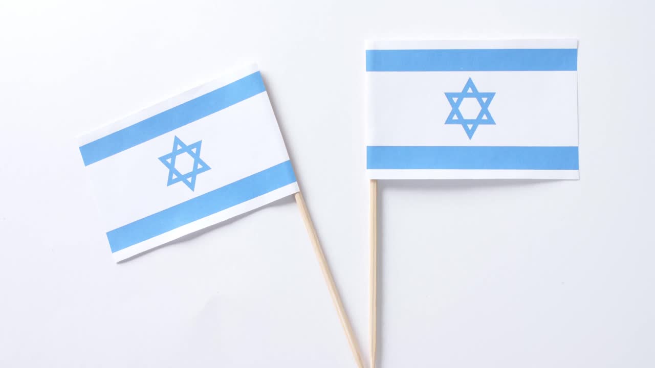 Primo piano di due bandiere di Israele adagiate su sfondo bianco.