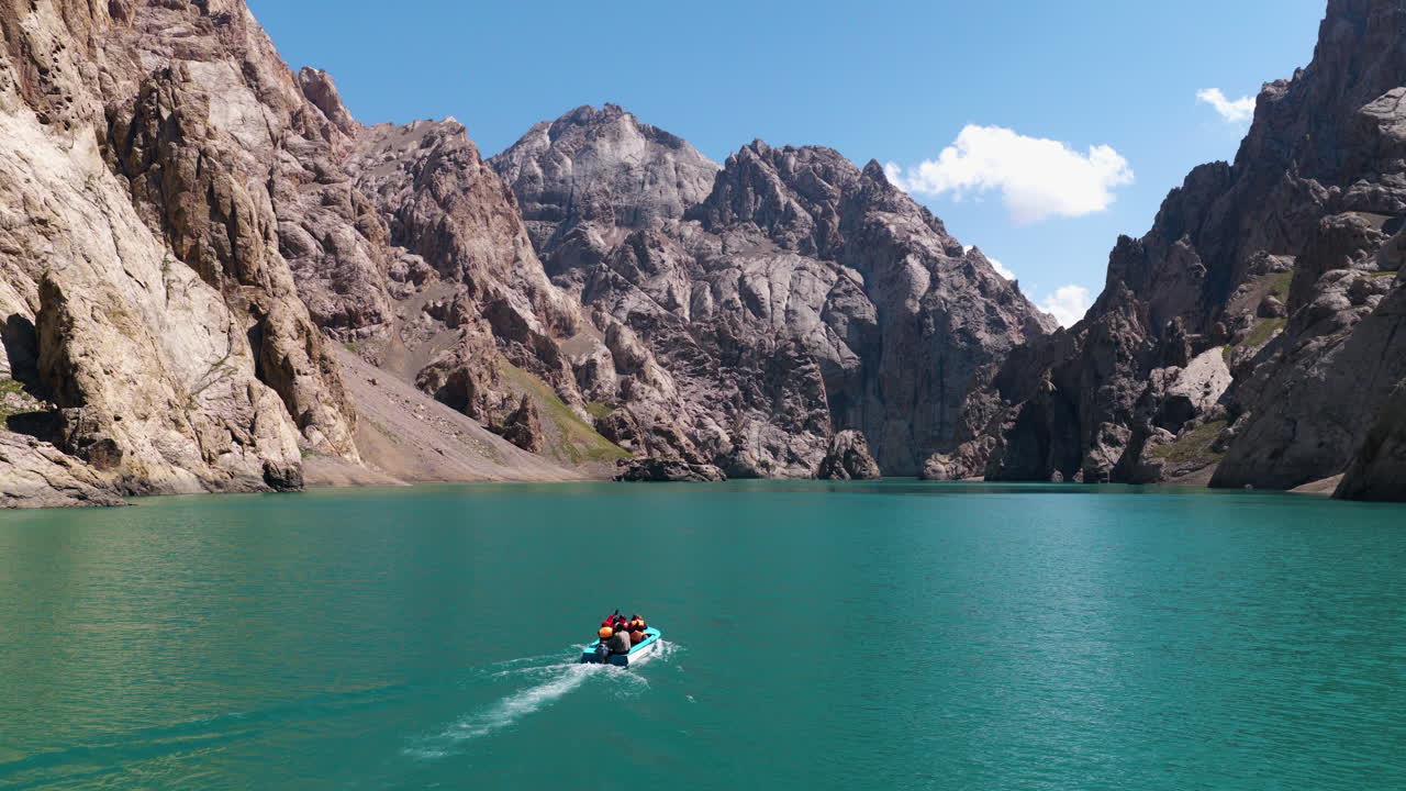 Tourists In A Motorboat Across The Emerald Waters Of Kel-Suu Lake In Kyrgyzstan. Aerial Wide Shot