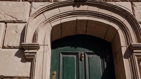 ornate green wooden door with brass hardware in a stone archway
