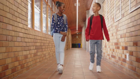 walking in school hallway, two kids with backpacks smiling and talking