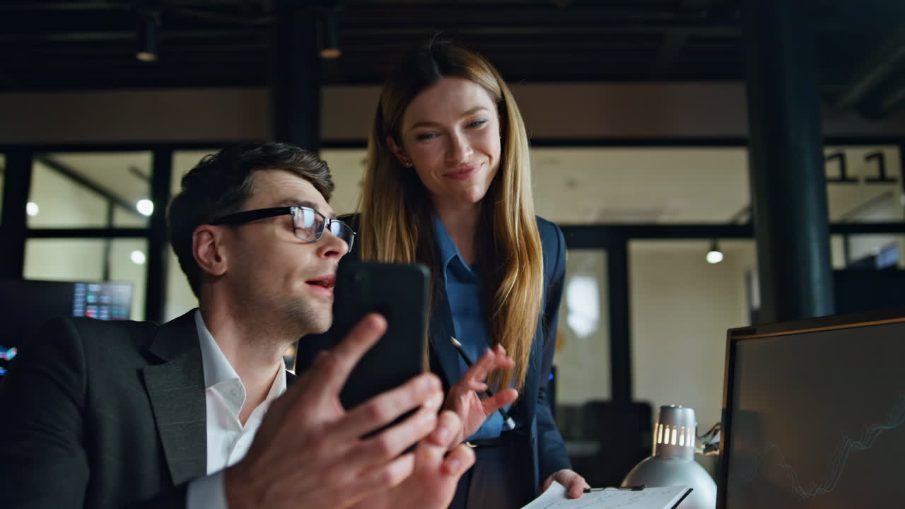 equipo de negocios trabajando hasta tarde mirando teléfono inteligente. colegas amigables comprobar móvil