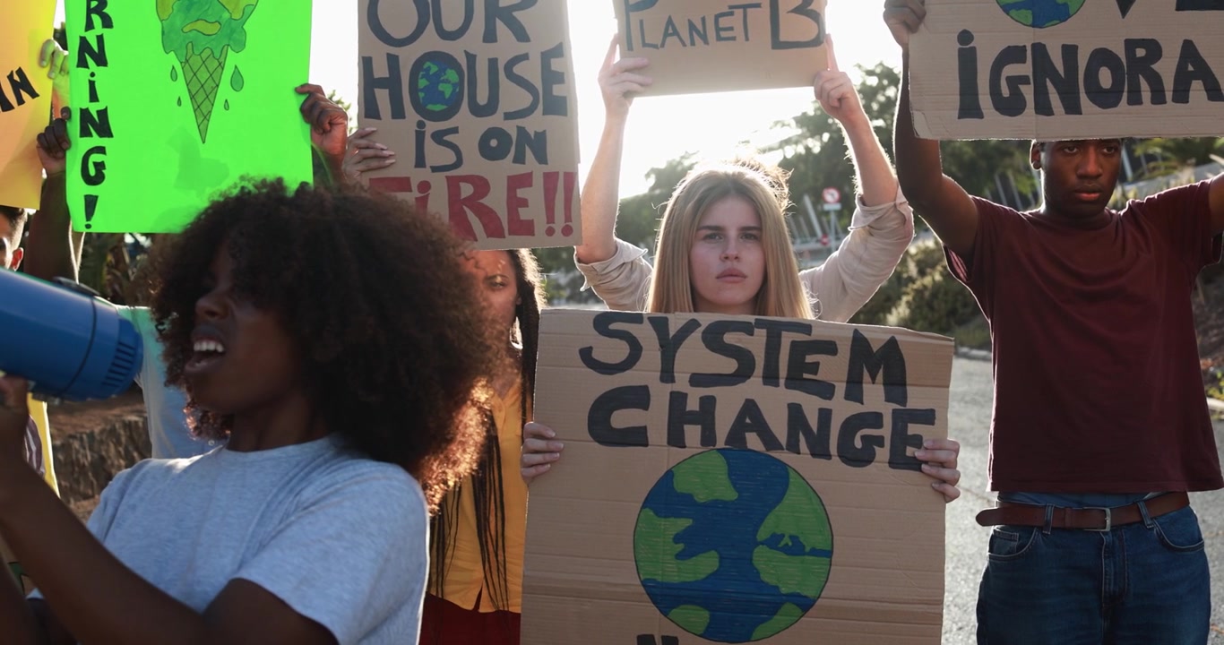Giovani attivisti con cartelli e megafono a una protesta per il cambiamento climatico