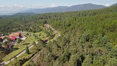 In-Tlaxcala,-Mexico,-a-small-hacienda-and-surrounding-forest-area-with-few-nearby-dwellings-are-visible-from-above-and-the-hill-can-be-seen-in-the-backdrop