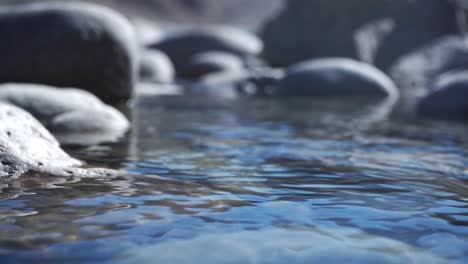 Agua-De-Lago-Transparente-Con-Rocas-En-La-Orilla-Durante-El-Verano