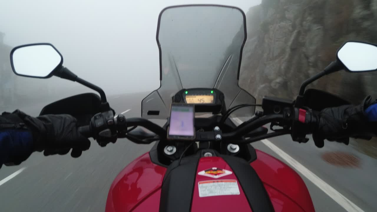 pov biker montar en motocicleta en la carretera en la fuerte lluvia con niebla por las montañas de austria