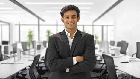 confident and happy indian businessman standing with crossed hands