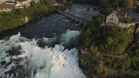 Toma-Aérea-En-Aproximación-A-Las-Cataratas-Del-Rin-Y-Donde-Se-Puede-Ver-El-Castillo-De-Laufen