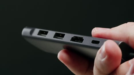 Close-up of a hand holding a portable gray USB hub