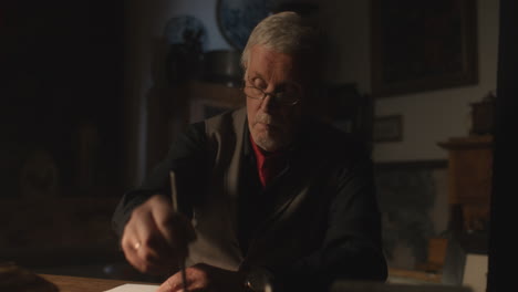 old passionate man writes a letter in his office at night