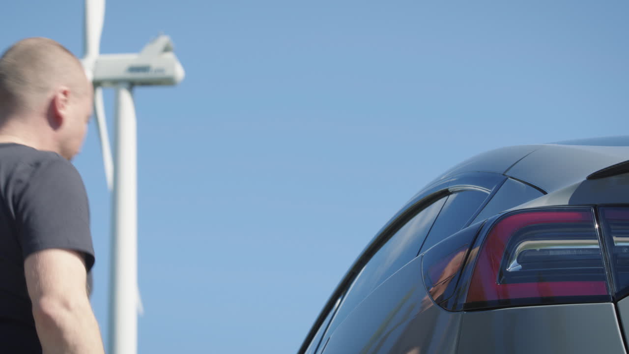 уменьшение масштаба, анимированная графика показывает поток электроэнергии и зарядку электромобиля перед ветряной турбиной