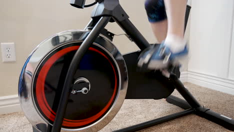 Woman-riding-stationary-bike---isolated-on-feet-peddling