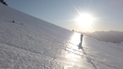 Dolly-in-following-a-man-skiing-alone-across-snow-covered-Piltriquitron-Hill-at-sunset,-El-Bolsón,-Patagonia-Argentina