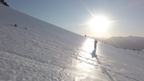 dolly in following a man skiing alone across snow covered piltriquitron hill at sunset, el bolsón, patagonia argentina