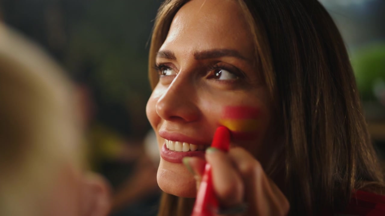 Woman Having Spanish Flag Painted on Her Cheek for Sports Event