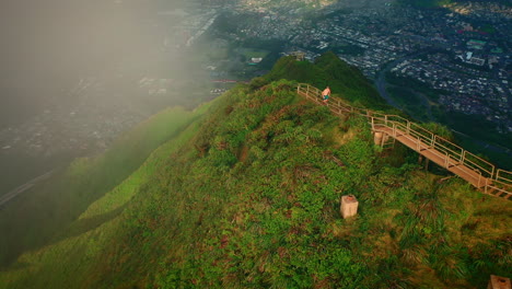 man running at stairway to heaven, aerial tracking shot at sunset, hawaii