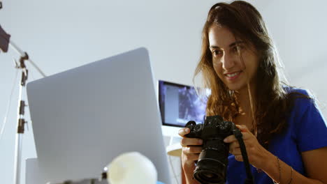 modelo femenino mirando una computadora portátil y una cámara digital 4k