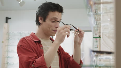 man trying on glasses in an optical store