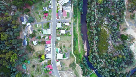 Top-down-aerial-small-town-along-narrow-river-Derby,-Tasmania