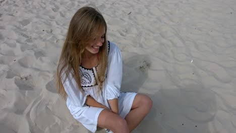 happy smiling girl sitting on sand on the beach.
