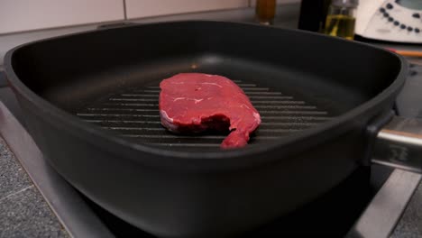 primer plano de un delicioso bistec en la sartén caliente durante la abrasión en una cocina en cámara lenta
