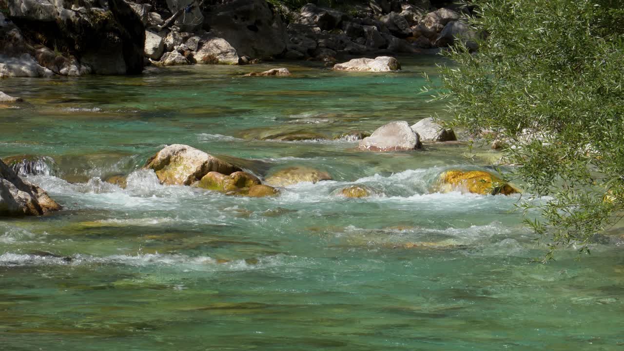 Acqua di fiume di montagna che si infrange sulle rocce del letto del fiume, proveniente dalle alte vette alpine