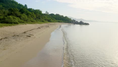 Drone-flying-fast-over-the-sand-of-a-jungle-beach-on-tropical-coast-brazilian-ocean,-Zimbros,-Santa-Catarina,-Brazil