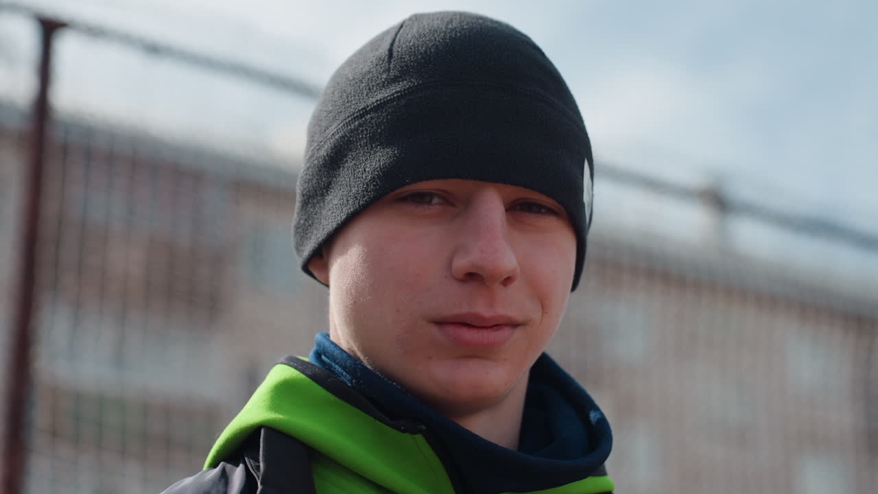 운동선수가 조용히 생각에 잠겨 있어요. 도시 스카이라인을 배경으로 사색에 잠긴 스포츠맨, 도시 풍경 근처에서 운동 후 생각에 잠긴 젊은 운동선수, 조용한 운동선수가 도시 배경의 폐쇄된 코트에서 잠시 멈춰 서 있어요.